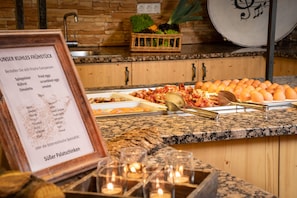 A buffet setup with various food items and a menu board. - KUHOTEL Steinplatte, Trademark Collection by Wyndham (Waidring)
