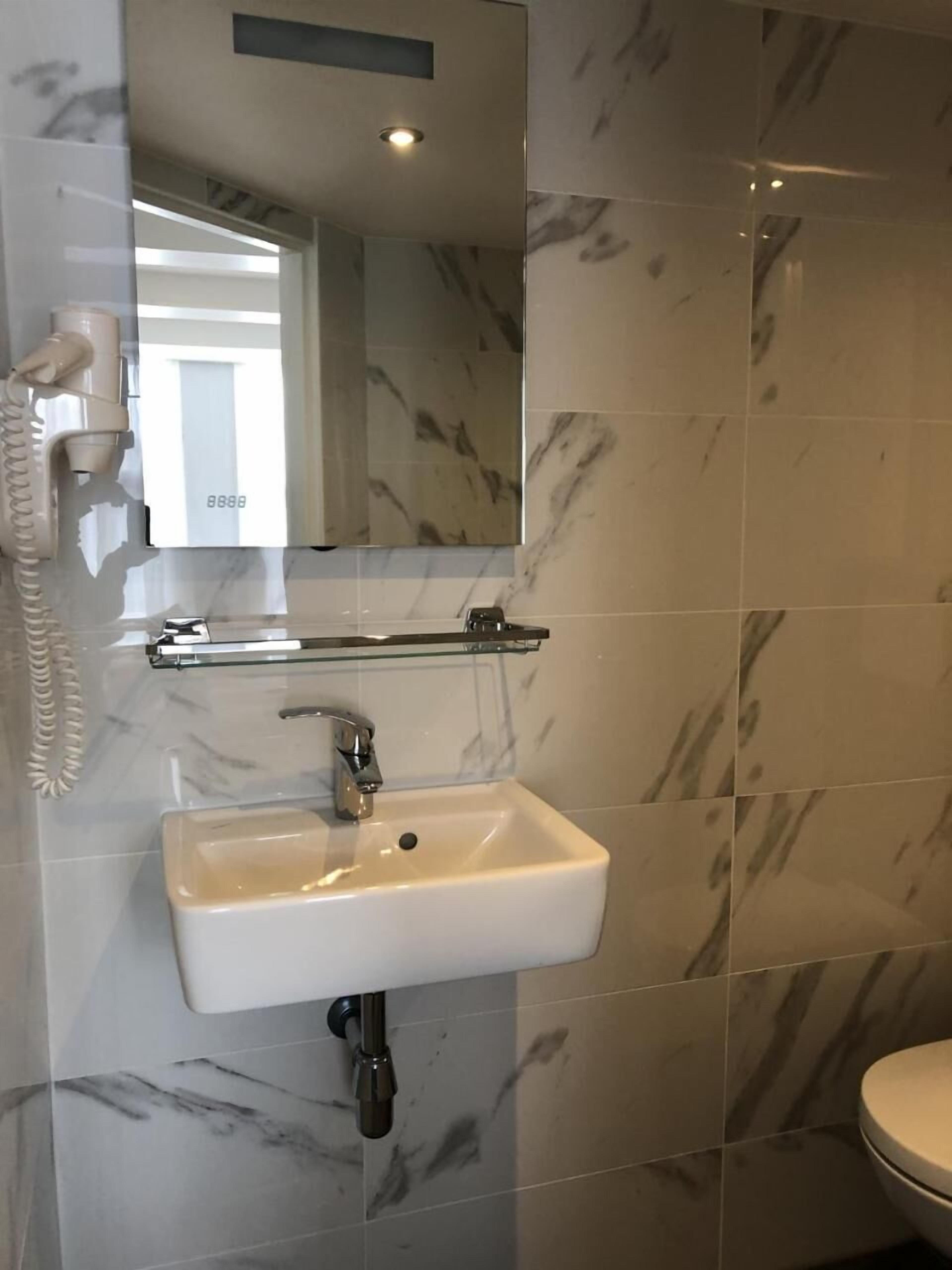 A bathroom with a white sink, a mirror, and a toilet.