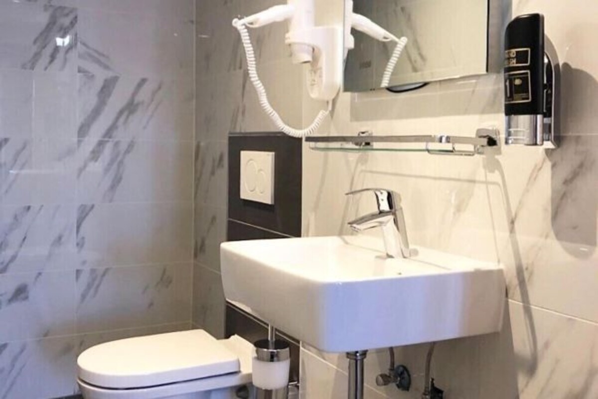 Un baño moderno con un lavabo blanco, un espejo y un inodoro.