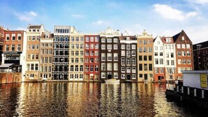 Uma fileira de edifícios coloridos ao longo de um canal com um barco na água.