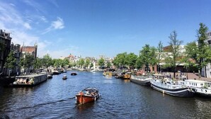Um canal com barcos, edifícios e árvores nas margens.