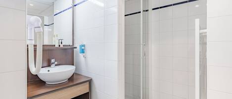 A modern bathroom with a white sink, wooden vanity, and a glass-enclosed shower.