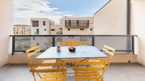 A balcony with a table and chairs, a bowl of fruit, and a potted plant. - Appart'City Classic Montélimar (Montélimar)