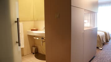 Habitació d'hotel amb bany, un llit i un armari.