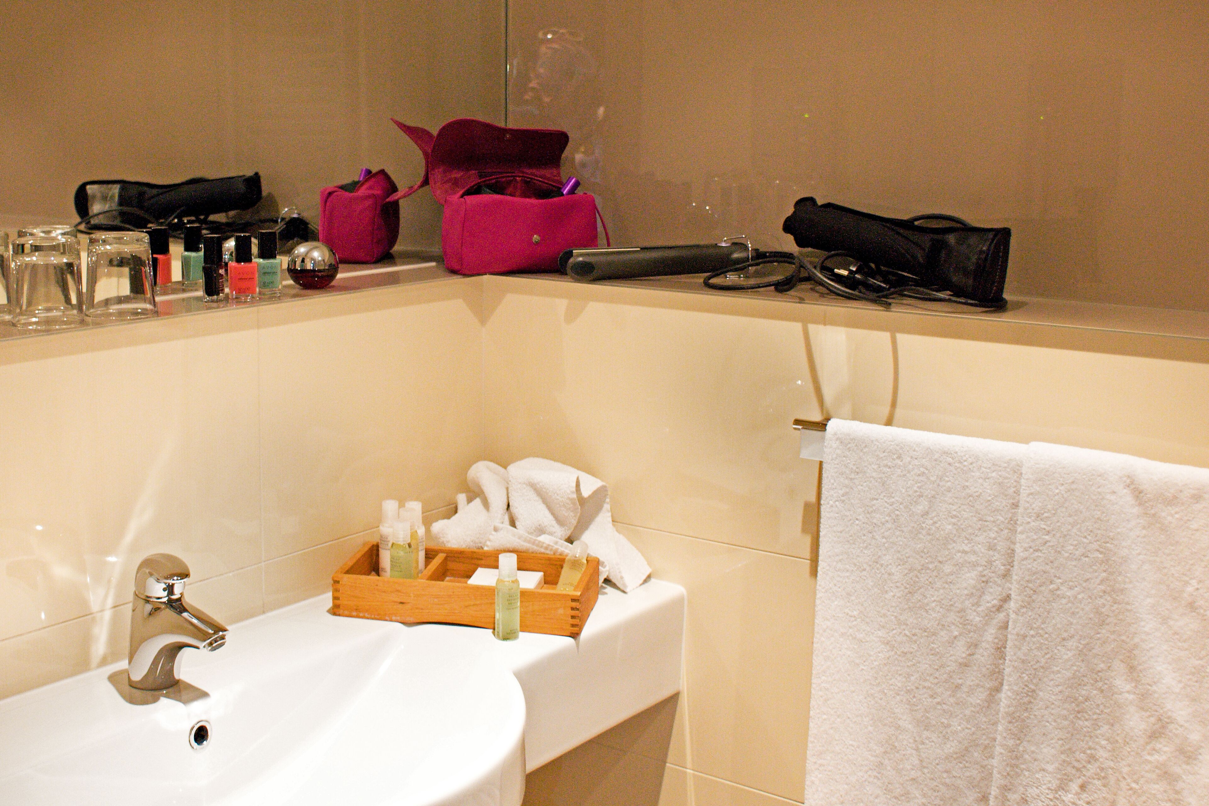 A bathroom with a sink, mirror, and toiletries on the counter.