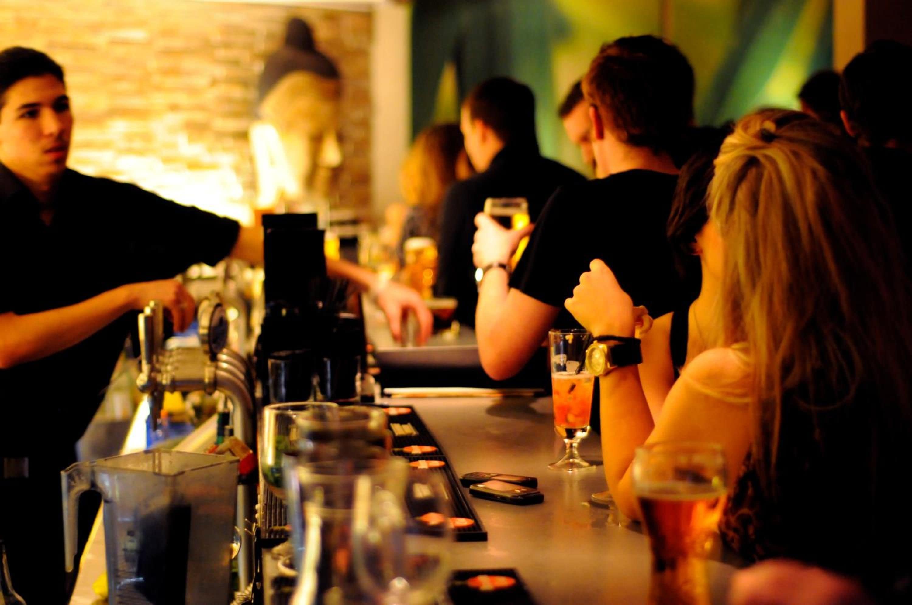 A bar setting with a bartender and patrons.