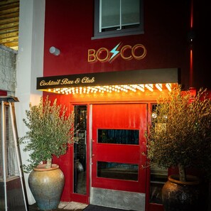 Un edificio con fachada roja y un letrero de neón que dice 'BOCO'.