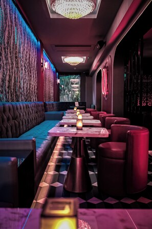 Un restaurante con suelo de cuadros, asientos tapizados en rojo y un papel tapiz estampado.