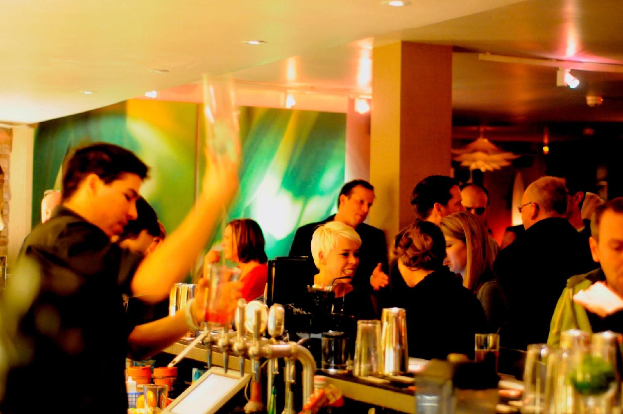 Eine Bar mit Barkeepern, die Gästen Getränke servieren.