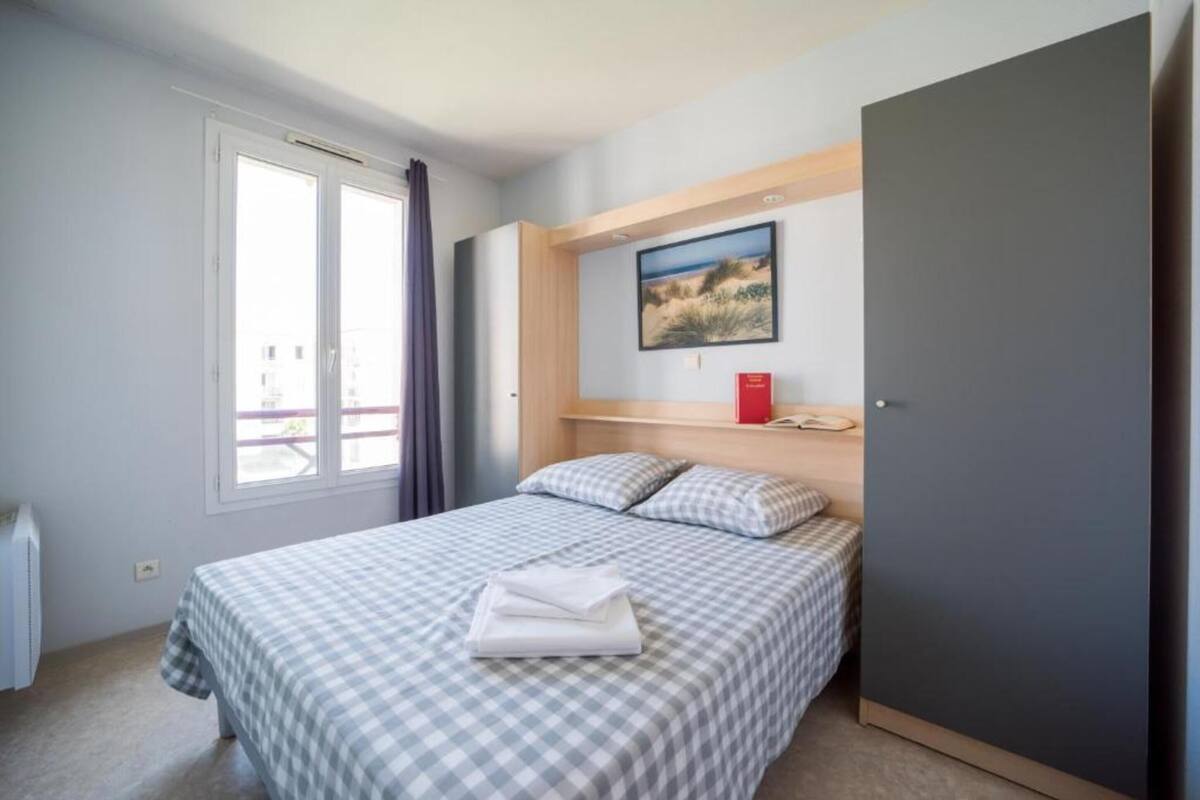 Quarto com cama, janela, quadro e guarda-roupa.