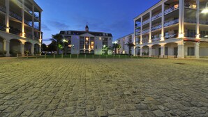 Un patio con pavimento de adoquines, rodeado de edificios de varios pisos con balcones y ventanas arqueadas.