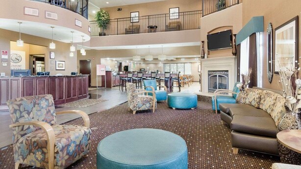 A spacious lobby with a high ceiling, multiple seating areas, a reception desk, and a fireplace.