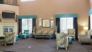 A spacious living area with a high ceiling, a fireplace, and a large window providing natural light.