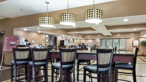 A hotel dining area with a buffet setup, multiple dining tables, and chairs.