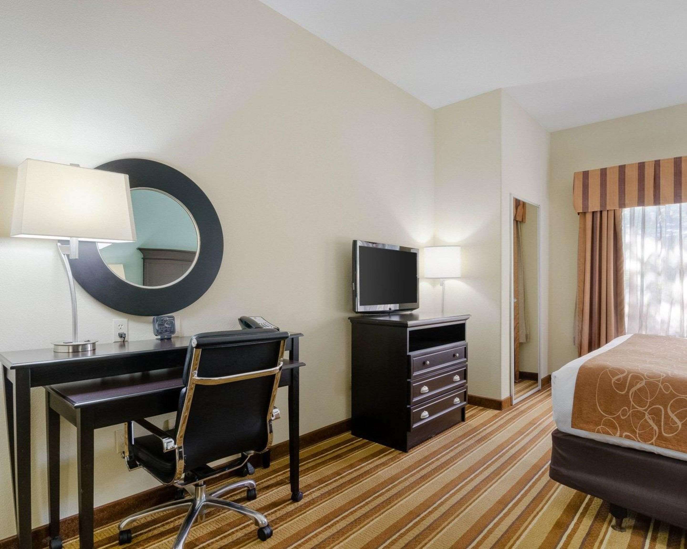 Ett hotellrum med ett skrivbord, en stol, en TV och en säng.