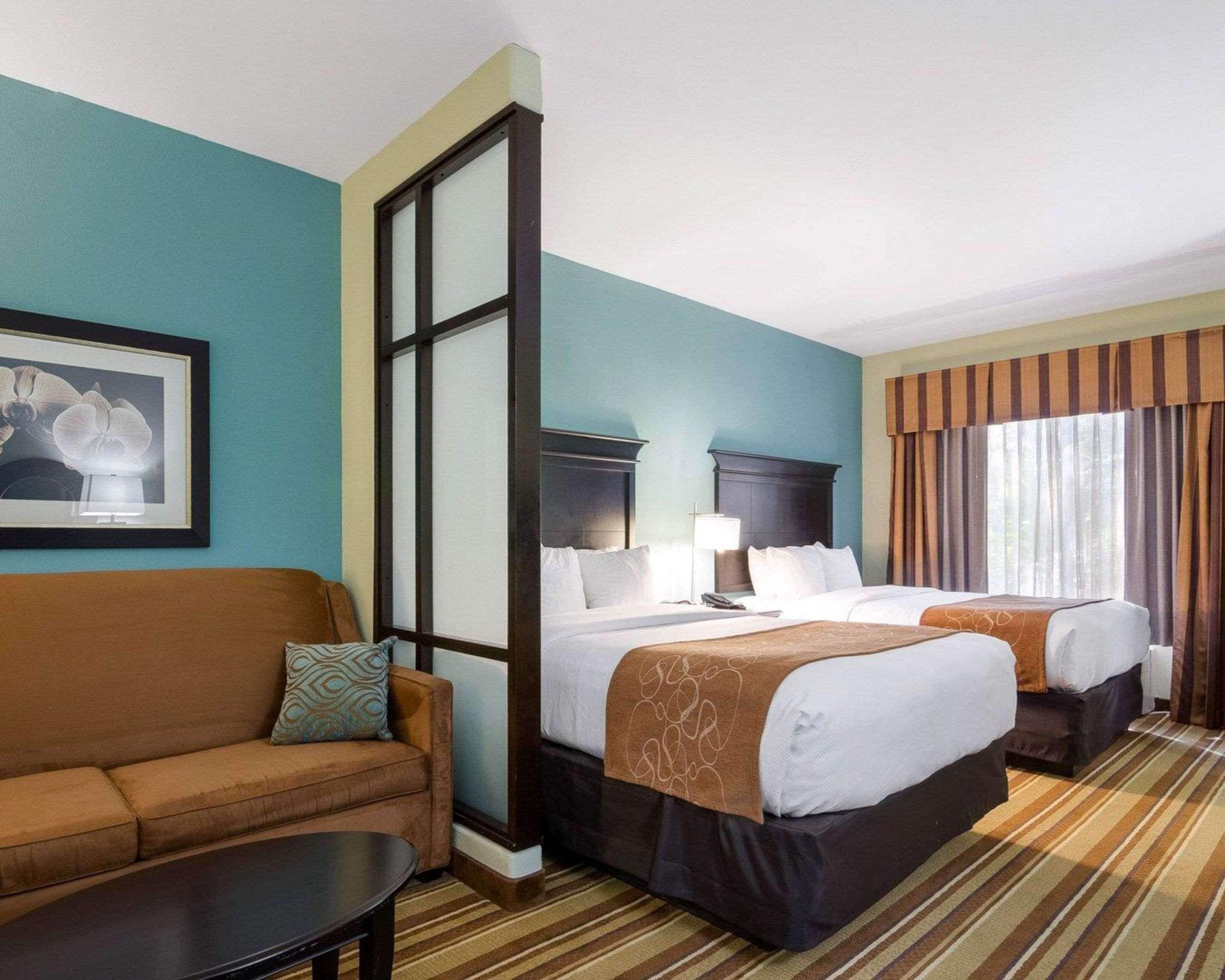 A hotel room with a large bed, a sofa, a small table, and a framed picture on the wall.