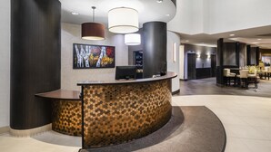 A reception area with a curved desk, modern pendant lighting, and a large abstract painting on the wall. - Best Western Premier Freeport Inn Calgary Airport (Calgary)