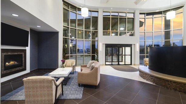A spacious lobby with a fireplace, comfortable seating, large windows, and a modern ceiling design. - Best Western Premier Freeport Inn Calgary Airport (Calgary)