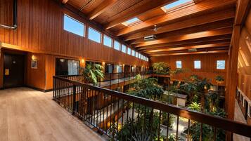 A multi-level atrium with wooden beams, balconies, and indoor plants.