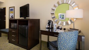 A hotel room with a desk, a television, a microwave, a refrigerator, a chair, a lamp, and a mirror. - Holiday Inn Express Hotel and Suites Scranton by IHG (Scranton)