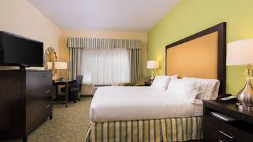 A hotel room with a bed, desk, television, and lamps.