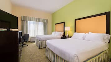 A hotel room with two beds, a desk, a chair, a television, and a window with curtains.