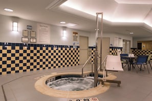 A hotel bathroom with a checkered wall, a hot tub, and a seating area with chairs and a table. - Holiday Inn Express Hotel and Suites Scranton by IHG (Scranton)