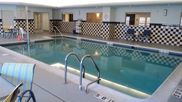 An indoor swimming pool with checkered tiles, a pool ladder, and a sign indicating a depth of 5 feet 0 inches.