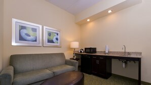 A compact hotel room with a sofa, a small table, a microwave, and a sink. - Holiday Inn Express Hotel and Suites Scranton by IHG (Scranton)
