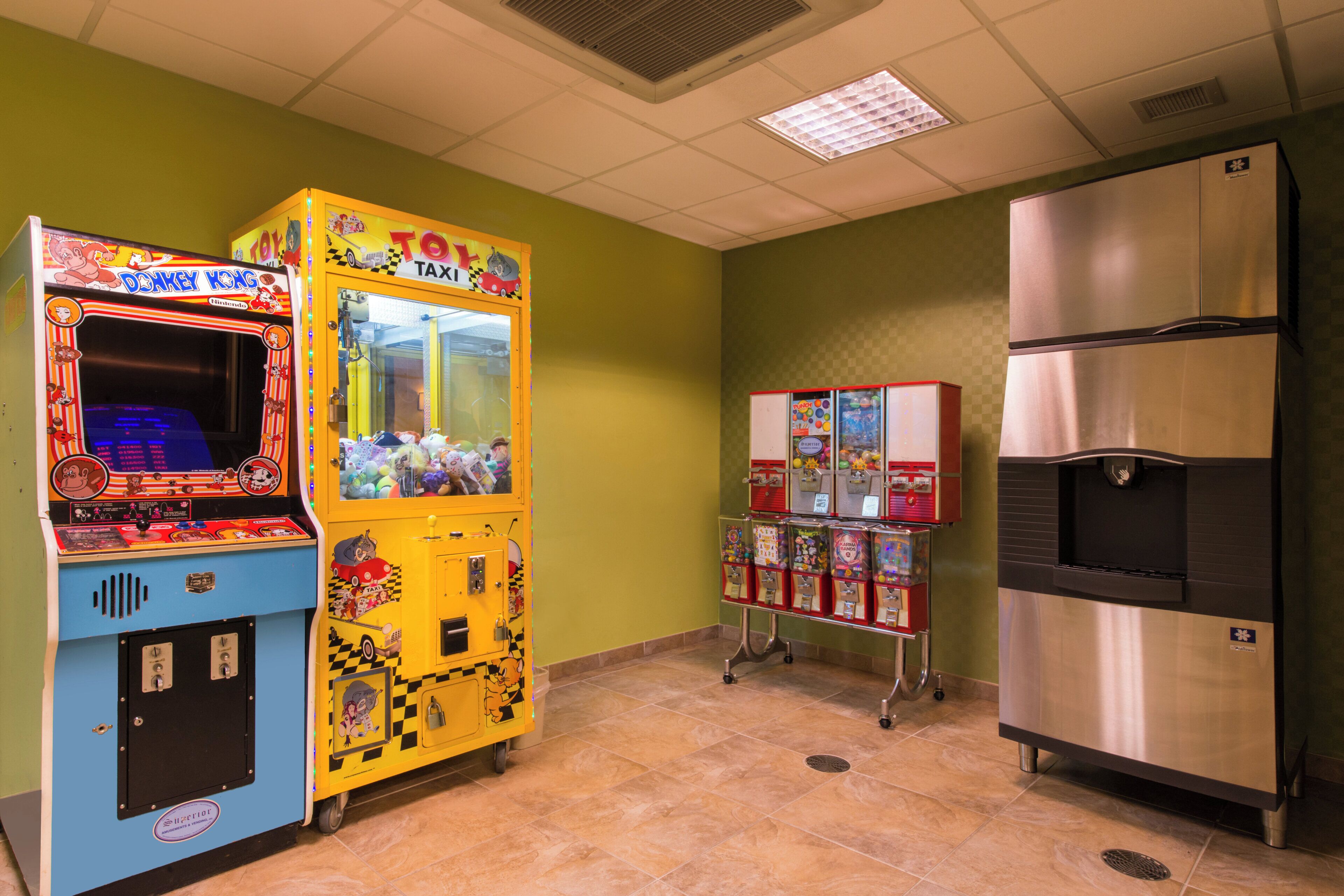 Una habitación con máquina expendedora, refrigerador y piso de baldosas.