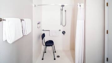 A shower area with a grab bar, a chair, and a towel rack.