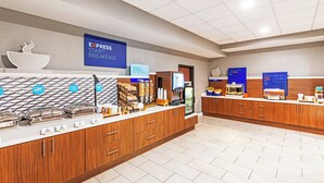 Un espace pour le petit-déjeuner à l’hôtel, aménagé avec un buffet proposant une variété d’aliments, et un panneau indiquant « PETIT-DÉJEUNER EXPRESS ».