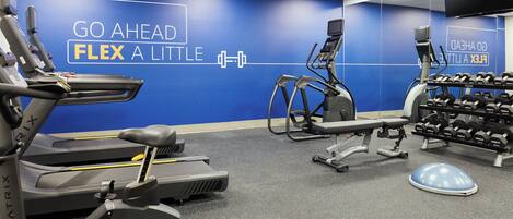 A gym with treadmills, elliptical machines, and a weight rack.
