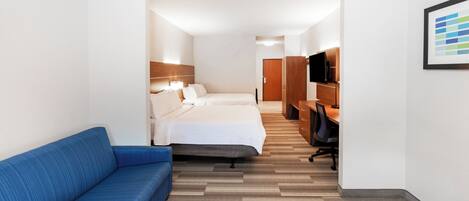 Een hotelkamer met een bed, een blauwe bank, een bureau met een stoel, een televisie en een ingelijst kunstwerk aan de muur.