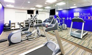 A gym with treadmills, elliptical machines, and weights.