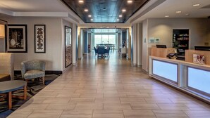 A hotel lobby with a reception desk, seating area, and a dining space.