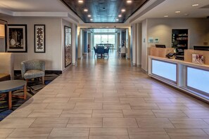 A hotel lobby with a reception desk, seating area, and a dining space.