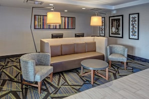 A modern lobby with a sofa, two armchairs, a small table, and a patterned carpet. - Holiday Inn Express Hotel & Suites Jackson NE by IHG (Jackson)