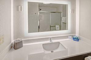 A bathroom with a large mirror, a sink, and a towel rack.