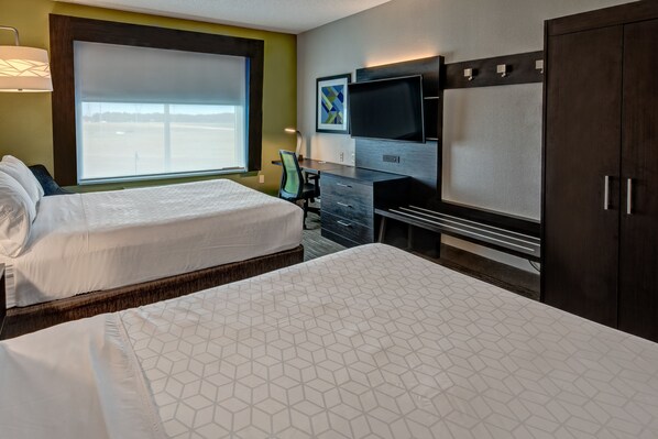 Una habitación de hotel con dos camas, un escritorio, una silla, un televisor y un armario.