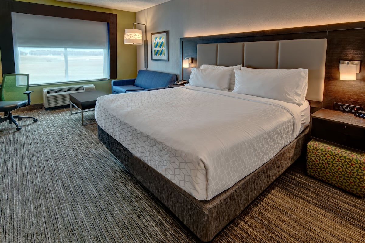Une chambre d’hôtel avec un grand lit, un bureau, une chaise et une vue sur l’extérieur.
