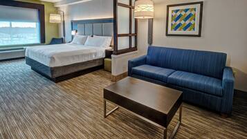 A hotel room with a bed, a sofa, a coffee table, and a large window.