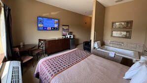 Hotelkamer met een bed, bureau, televisie, badkamer en uitzicht op het omliggende landschap.