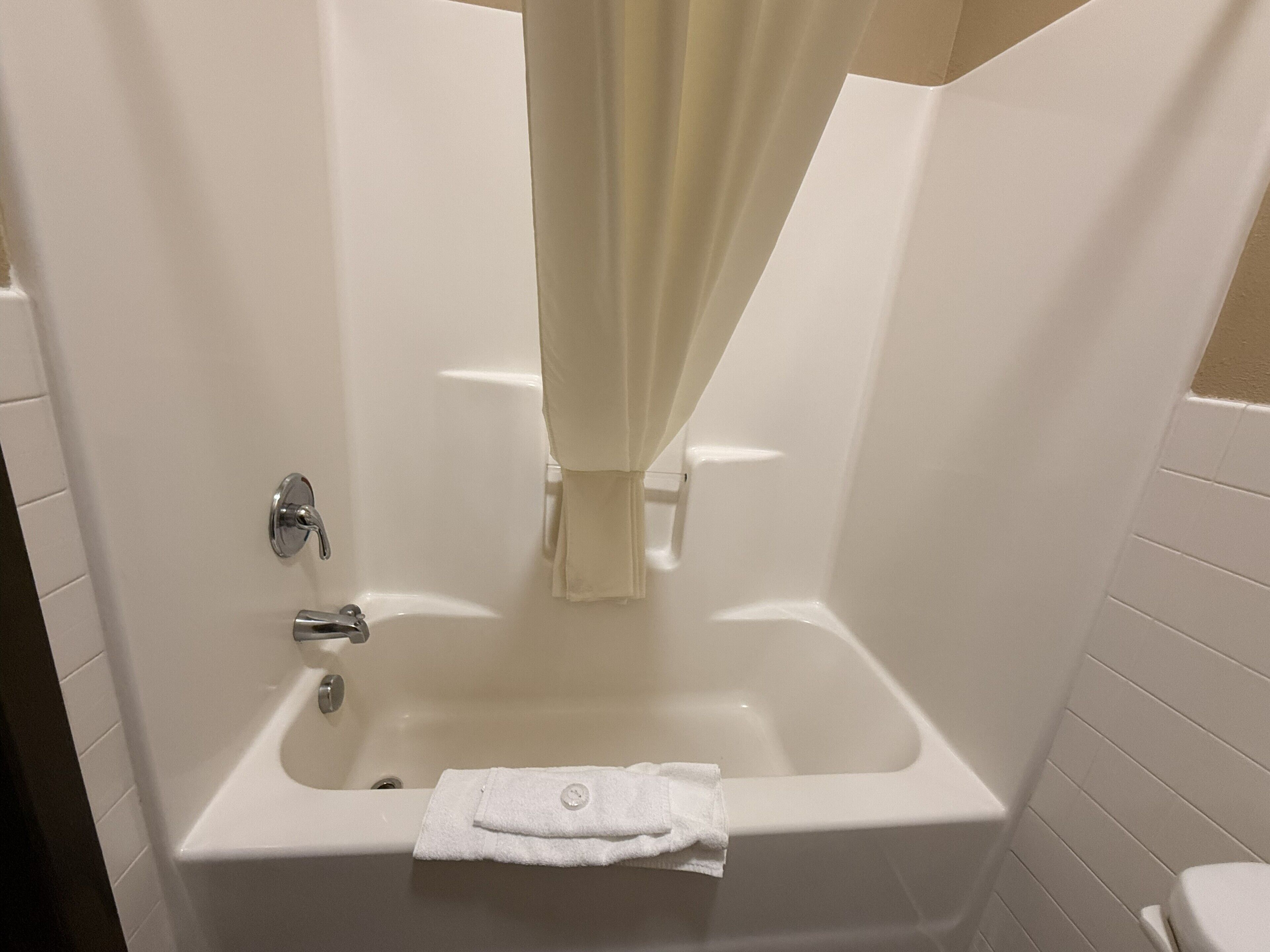 Une salle de bain avec une baignoire, une serviette et un rideau.