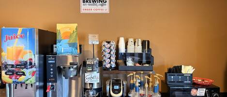 A coffee station with a juice dispenser, a coffee machine, a Torani syrup dispenser, and a microwave.