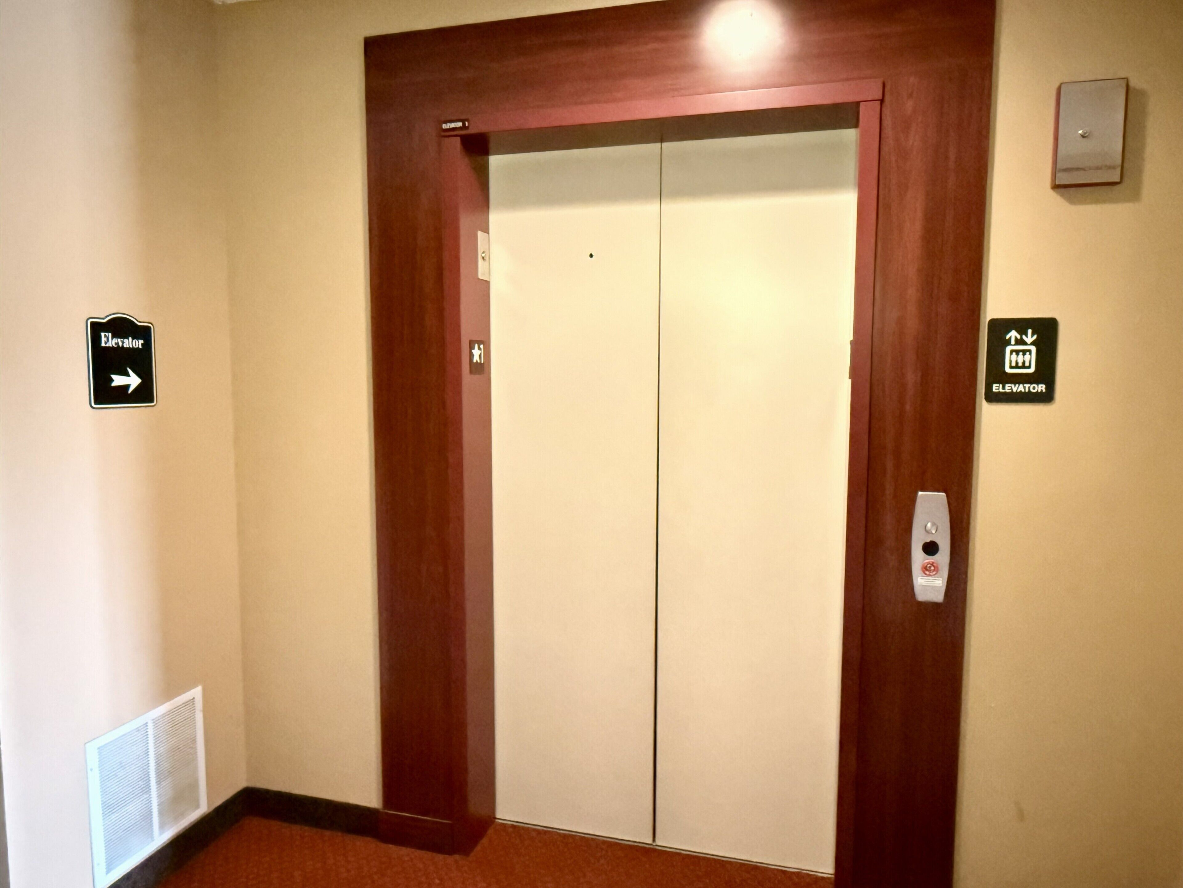An elevator with a sign indicating its direction and a control panel with a button.