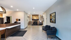 Un moderno vestíbulo de hotel con mostrador de recepción, zona de estar y chimenea.