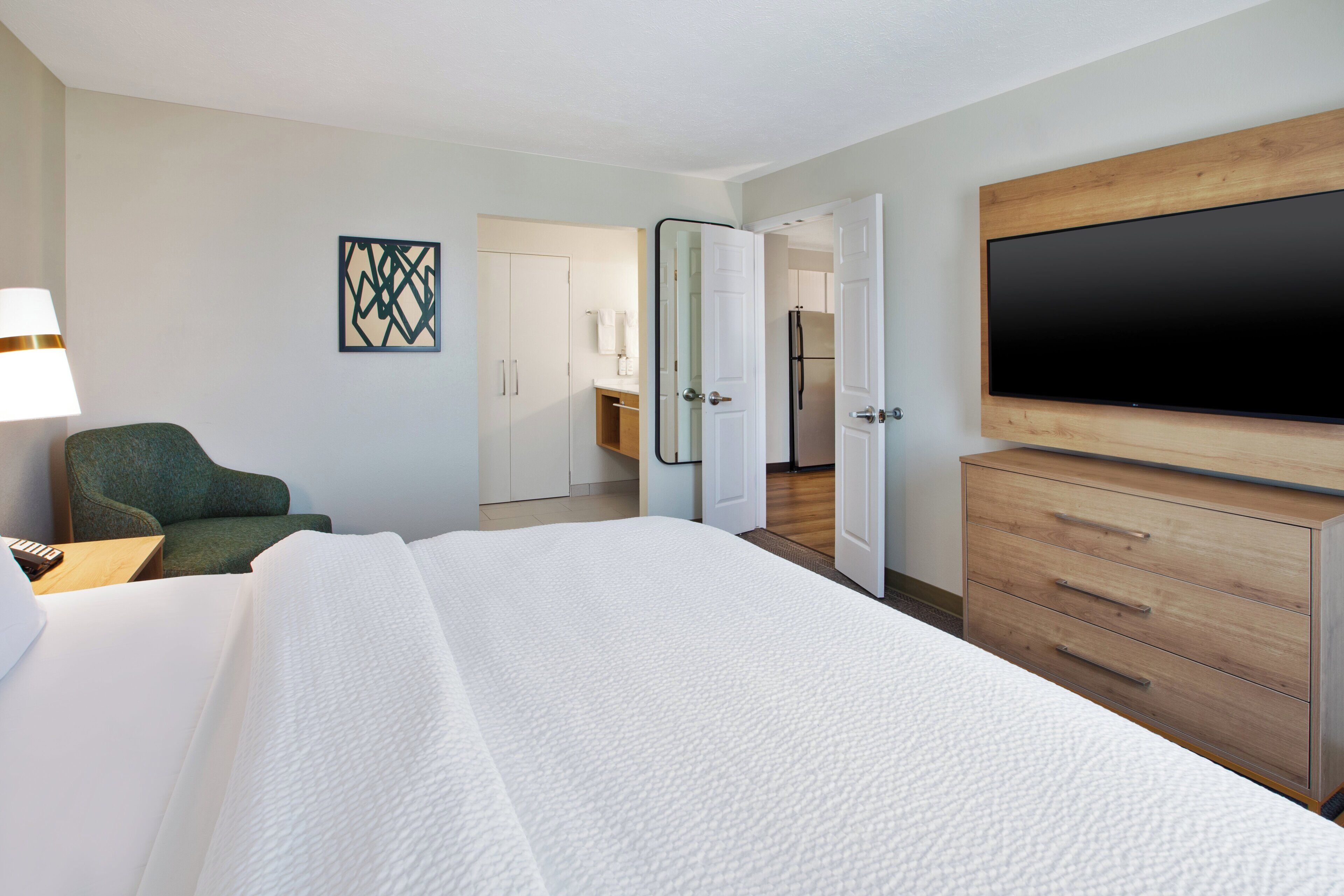 Una habitación de hotel con cama, televisión, escritorio y silla.