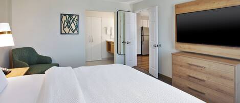 Una habitación de hotel con cama, televisión, escritorio y silla.
