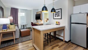 Cocina moderna con una isla central, suelo de madera e iluminación colgante.